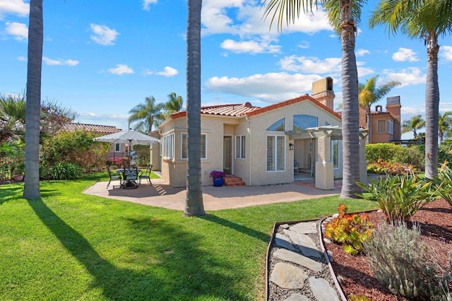 rear view of property featuring a tiled roof, a lawn, a patio area, and stucco siding