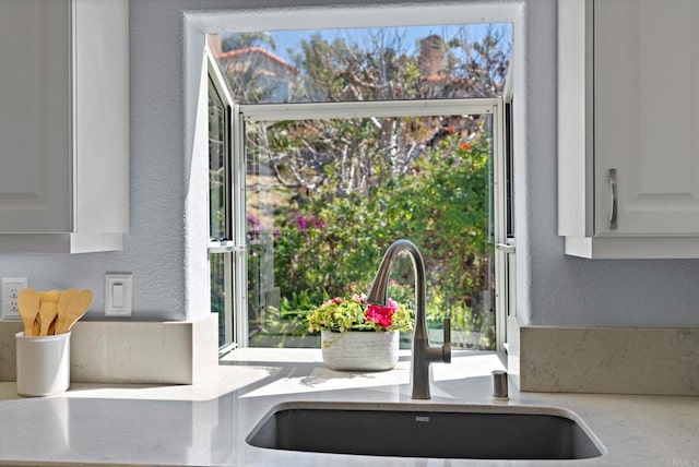 interior details featuring white cabinets, a sink, and a textured wall