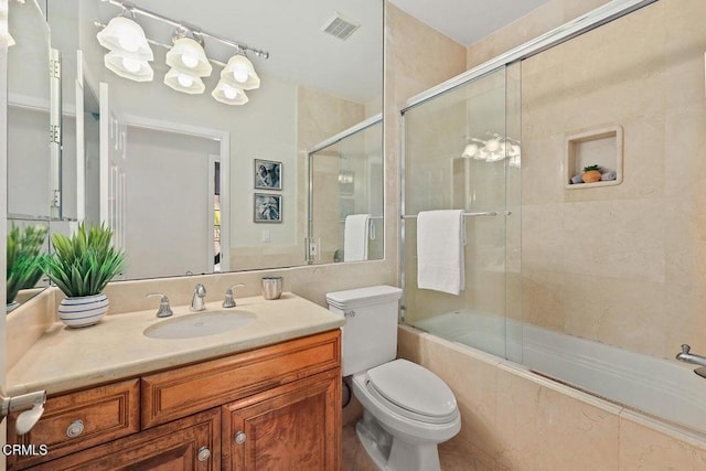 full bathroom with toilet, combined bath / shower with glass door, vanity, and visible vents