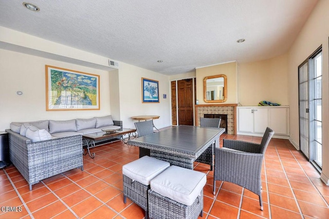 dining room featuring visible vents, a fireplace, a textured ceiling, and light tile patterned floors