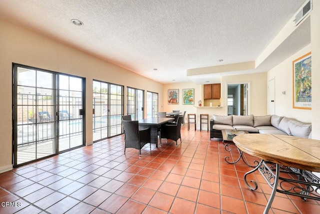 living area with light tile patterned floors, a textured ceiling, and visible vents