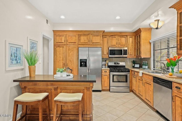 kitchen featuring backsplash, appliances with stainless steel finishes, brown cabinets, and a sink