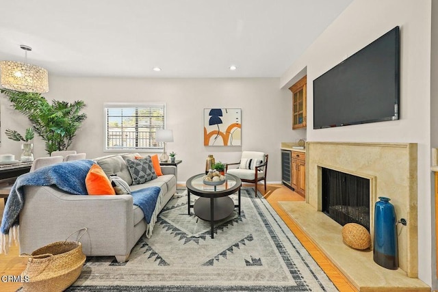 living area featuring wine cooler, light wood finished floors, recessed lighting, a high end fireplace, and baseboards