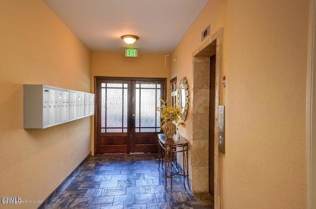 doorway with visible vents, stone tile flooring, mail area, and baseboards