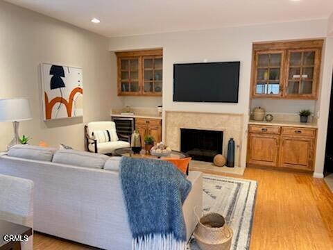 living area with a fireplace with raised hearth, light wood-type flooring, and recessed lighting