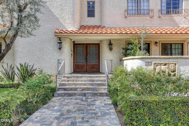 entrance to property with stucco siding, a tile roof, and french doors