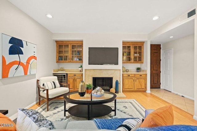 living area with light wood finished floors, baseboards, visible vents, a premium fireplace, and recessed lighting