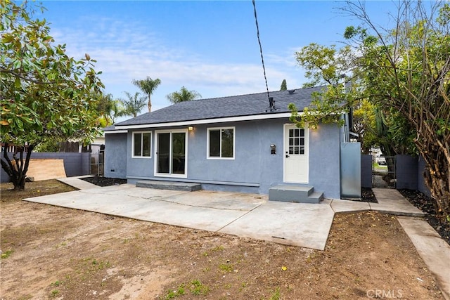 rear view of property with a patio area, fence, and stucco siding