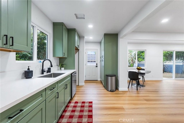 kitchen featuring light wood-style flooring, a sink, light countertops, dishwasher, and green cabinetry