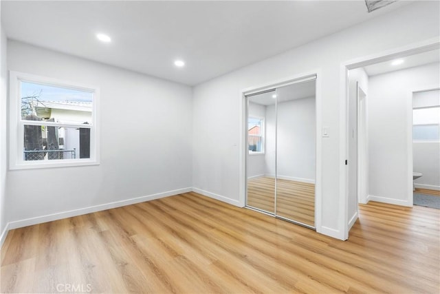 unfurnished bedroom with ensuite bathroom, light wood-style flooring, recessed lighting, baseboards, and a closet