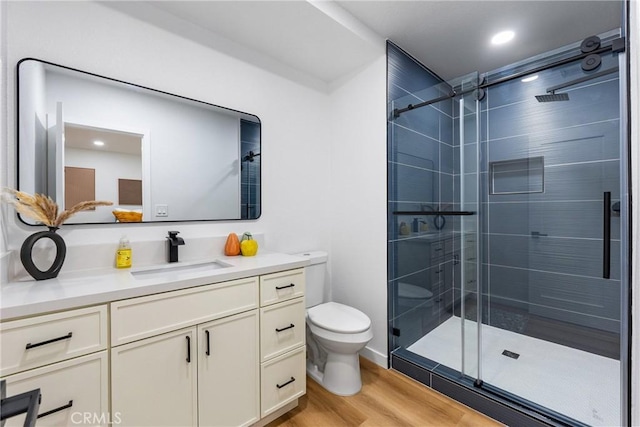 bathroom with vanity, a shower stall, toilet, and wood finished floors