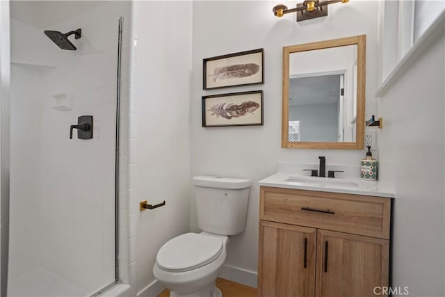 bathroom featuring toilet, baseboards, a tile shower, and vanity