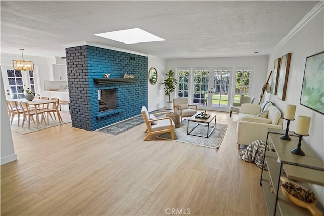 living room with french doors, ornamental molding, a brick fireplace, a textured ceiling, and wood finished floors