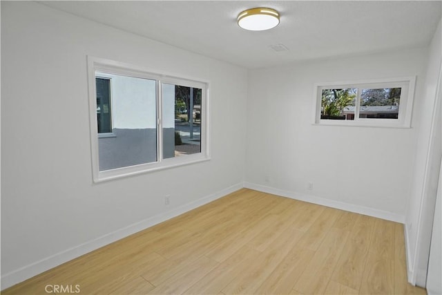 unfurnished room featuring a healthy amount of sunlight, baseboards, and wood finished floors