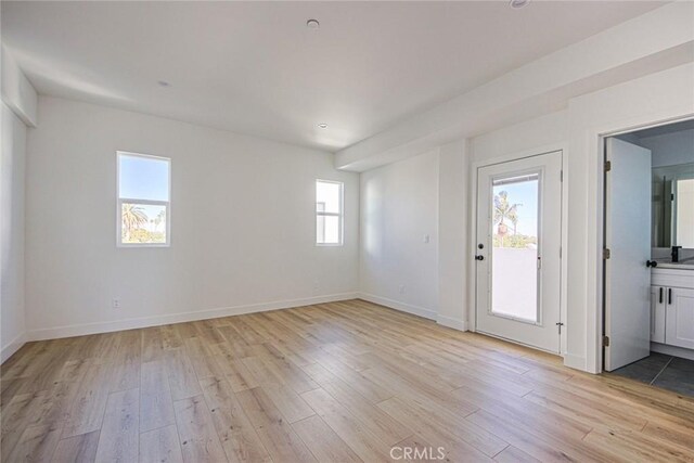 spare room with light wood-style flooring and baseboards