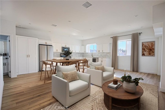 living area with visible vents, light wood-style flooring, and baseboards