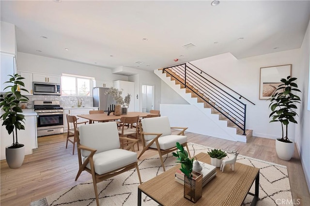 living room with recessed lighting, visible vents, stairway, and light wood finished floors