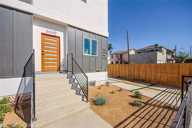 entrance to property with board and batten siding and fence