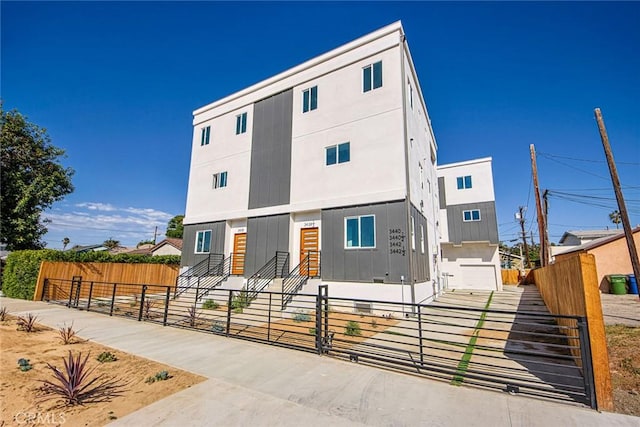 view of front of home featuring entry steps, a fenced front yard, a gate, and stucco siding