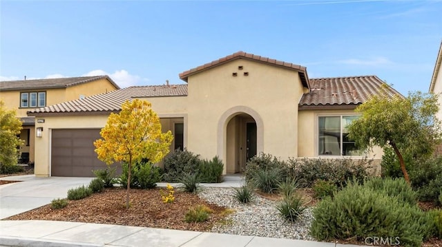 mediterranean / spanish-style house with a garage, a tile roof, concrete driveway, and stucco siding