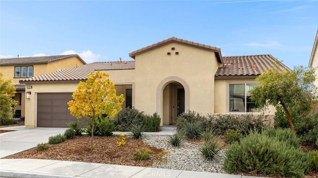 mediterranean / spanish house featuring stucco siding, an attached garage, driveway, and a tiled roof