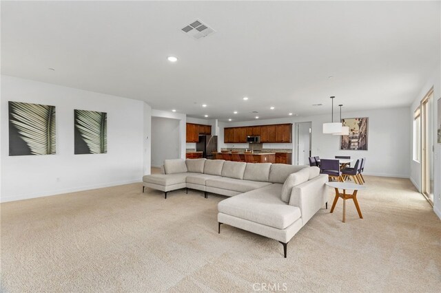 living room with visible vents, baseboards, light colored carpet, and recessed lighting