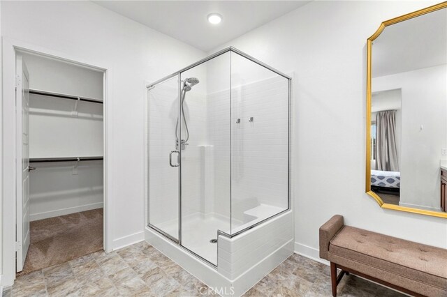 full bathroom with a stall shower, a walk in closet, and baseboards