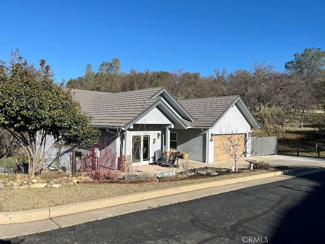 view of front of house with an attached garage, fence, a tiled roof, concrete driveway, and stucco siding