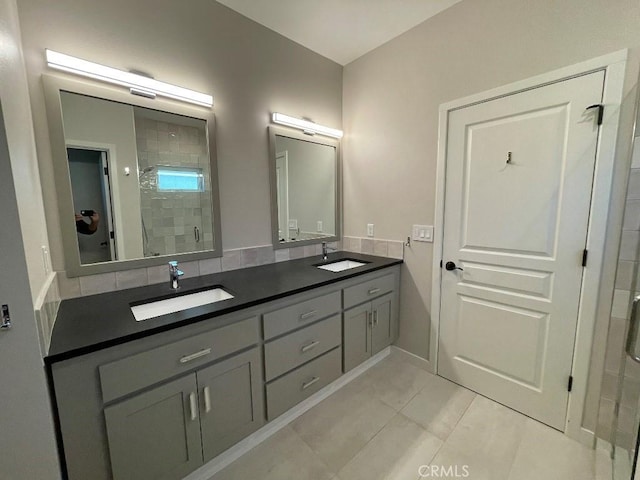 full bathroom with double vanity, a stall shower, and a sink