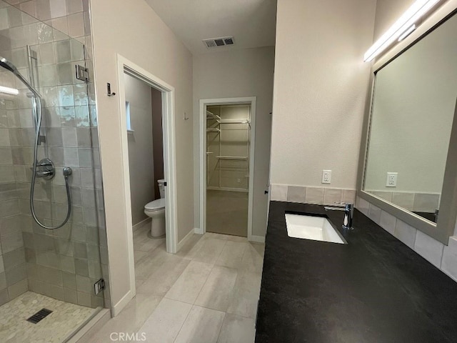 bathroom featuring a stall shower, visible vents, toilet, a walk in closet, and vanity