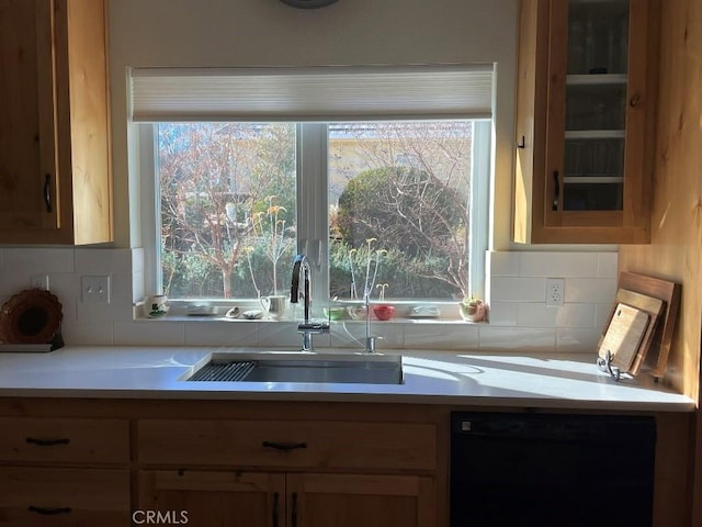 kitchen featuring light countertops, a sink, backsplash, and dishwasher