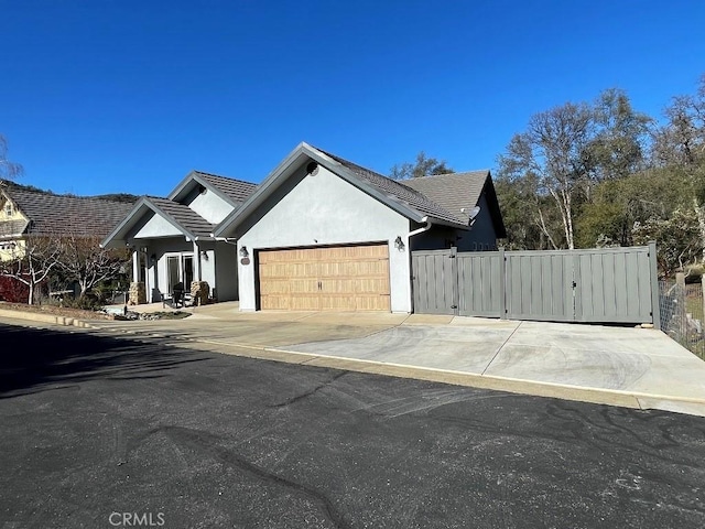 modern farmhouse style home featuring an attached garage, fence, concrete driveway, a gate, and stucco siding