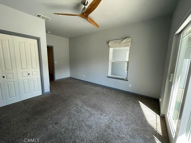 unfurnished bedroom featuring a ceiling fan, visible vents, baseboards, a closet, and dark colored carpet