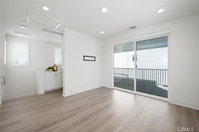 empty room with attic access, visible vents, wood finished floors, and recessed lighting