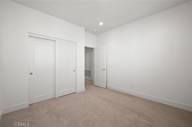 unfurnished bedroom with recessed lighting, a closet, light colored carpet, visible vents, and baseboards