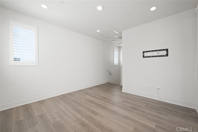 spare room with light wood-style flooring, attic access, baseboards, and recessed lighting