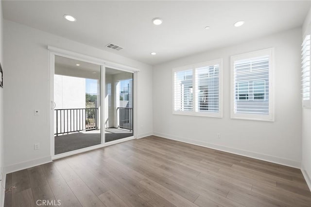 spare room with recessed lighting, wood finished floors, visible vents, and baseboards