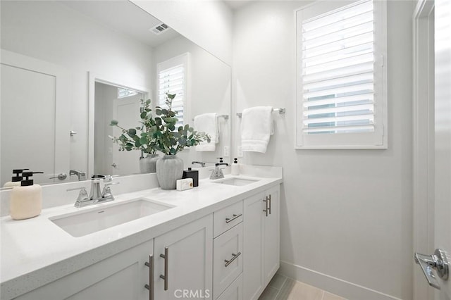 full bath with double vanity, baseboards, visible vents, and a sink