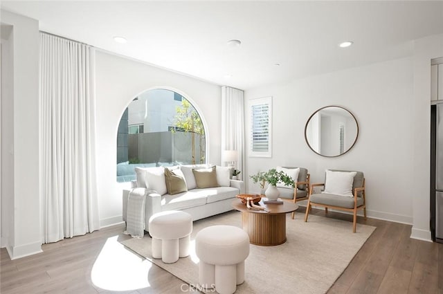 living area featuring light wood-type flooring, baseboards, and recessed lighting