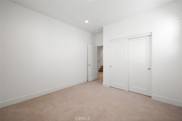 unfurnished bedroom with recessed lighting, baseboards, a closet, and light colored carpet