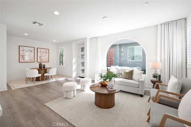 living room with baseboards, wood finished floors, visible vents, and recessed lighting