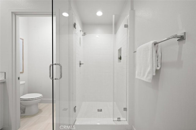 bathroom with a stall shower, baseboards, and toilet