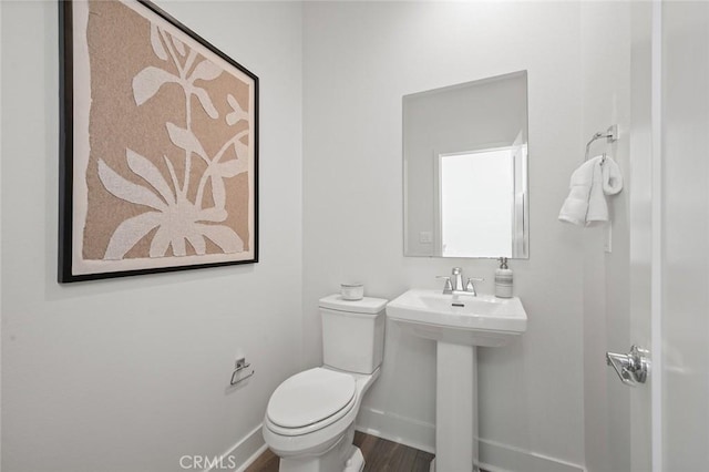 bathroom with toilet, a sink, baseboards, and wood finished floors