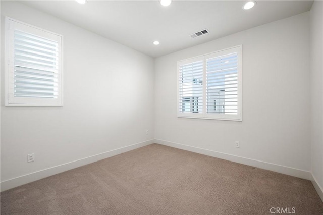 spare room featuring baseboards, light carpet, visible vents, and recessed lighting