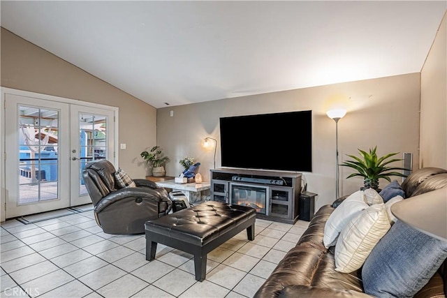 living room with lofted ceiling, light tile patterned floors, a glass covered fireplace, and french doors