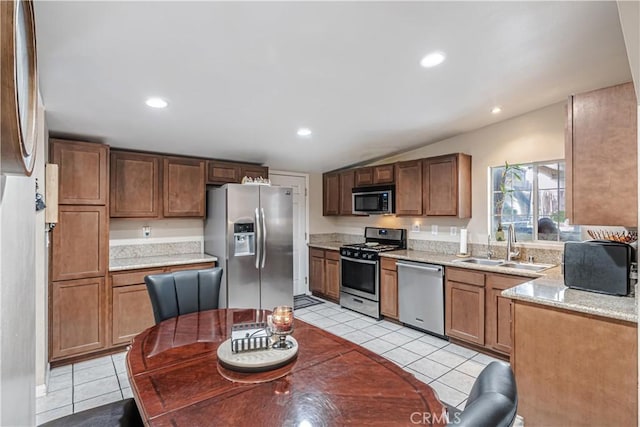 kitchen with light tile patterned floors, vaulted ceiling, stainless steel appliances, a sink, and recessed lighting