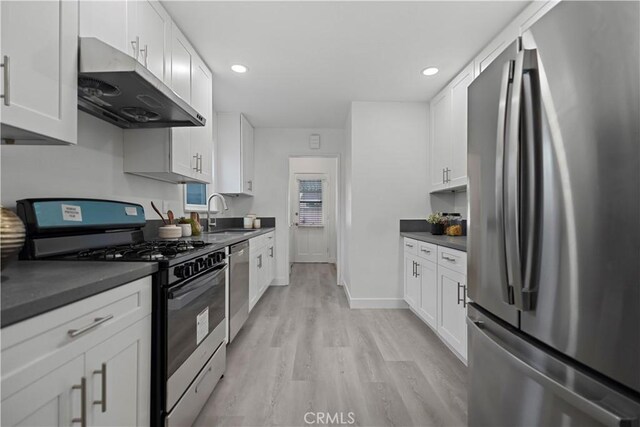 kitchen featuring stainless steel appliances, dark countertops, white cabinetry, a sink, and under cabinet range hood