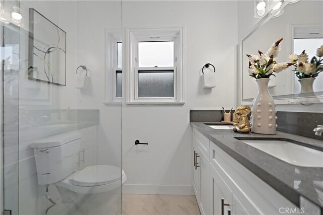 bathroom with toilet, a sink, baseboards, marble finish floor, and double vanity