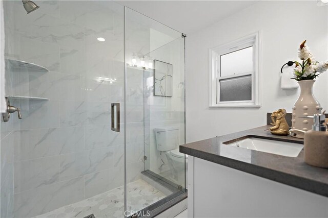 full bath with toilet, a marble finish shower, and vanity