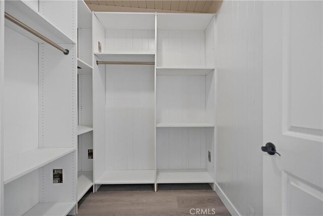 walk in closet with wood finished floors